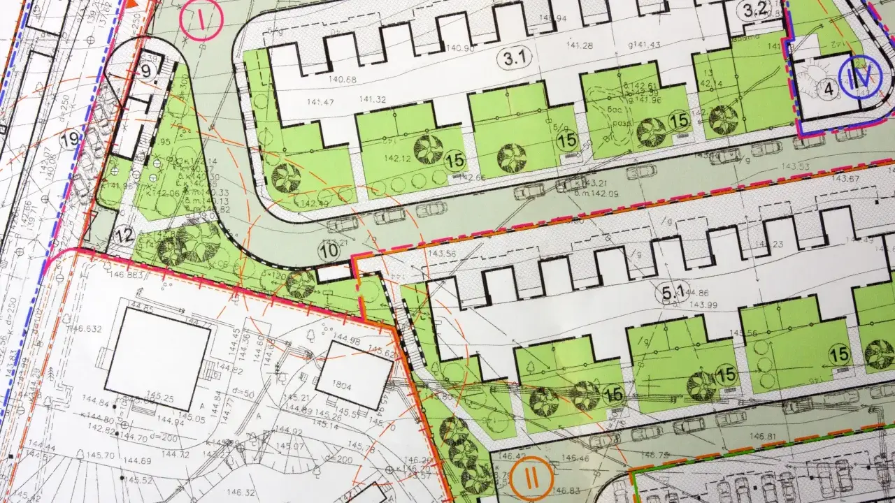 Plan zagospodarowania terenu z zaznaczonymi strefami zabudowy, zielenią, drogami i parkingami. Widoczne numery działek i oznaczenia budynków.