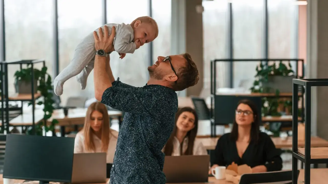 Szczęśliwy ojciec podrzuca dziecko w biurze, gdzie pracują kobiety. Czy urlop wychowawczy wlicza się do stażu pracy?