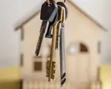 Pęk kluczy wisi na tle miniaturowego domu. Czy to symbol nowego początku, czy może niechcianego wywłaszczenia?