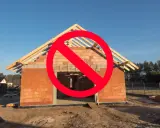 Budowa domu w toku, ale czerwony znak zakazu sugeruje problemy z legalizacją samowoli budowlanej.