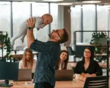 Szczęśliwy ojciec podrzuca dziecko w biurze, gdzie pracują kobiety. Czy urlop wychowawczy wlicza się do stażu pracy?