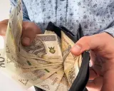 Dłoń pokazuje plik banknotów 200 zł w portfelu. To symbol nagrody jubileuszowej za 40 lat pracy w budżetówce.