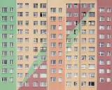 Wielopiętrowy blok mieszkalny z kolorowymi pasami. Wiele okien, każde z nich to potencjalne spółdzielcze własnościowe prawo do lokalu.