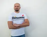 Mężczyzna w koszulce z napisem "Równość Ogólnopolski związek zawodowy" stoi z rękami skrzyżowanymi na piersi.