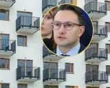 Mężczyzna w okularach przemawia na tle nowoczesnego bloku z balkonami, dyskutując o problemach najmu krótkoterminowego.