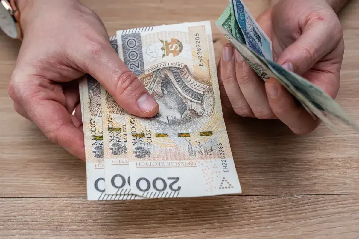 Ręce trzymają polskie banknoty 200 zł. Czy to już czas na 13 pensję w 2026 roku?