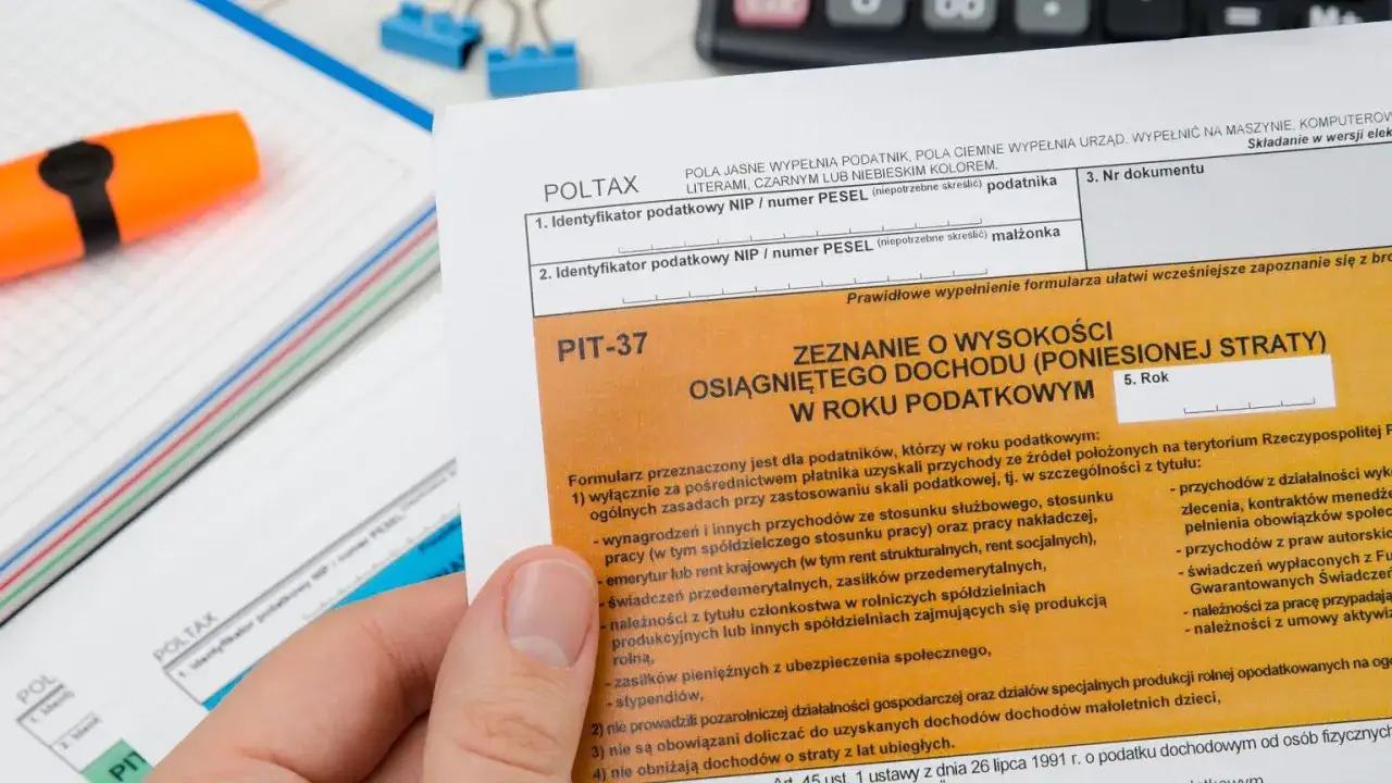 Formularz PIT-37 do rozliczenia dochodów za rok 2025. Dłoń trzyma dokument podatkowy.